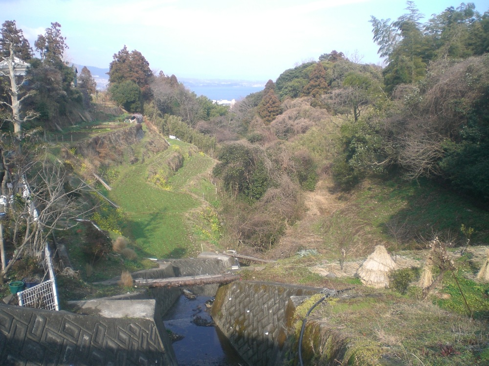 Un petit ruisseau à côté des habitations: un tronc d'arbre sert de pont pour les habitants qui veulent aller dans leur jardin, de l'autre côté