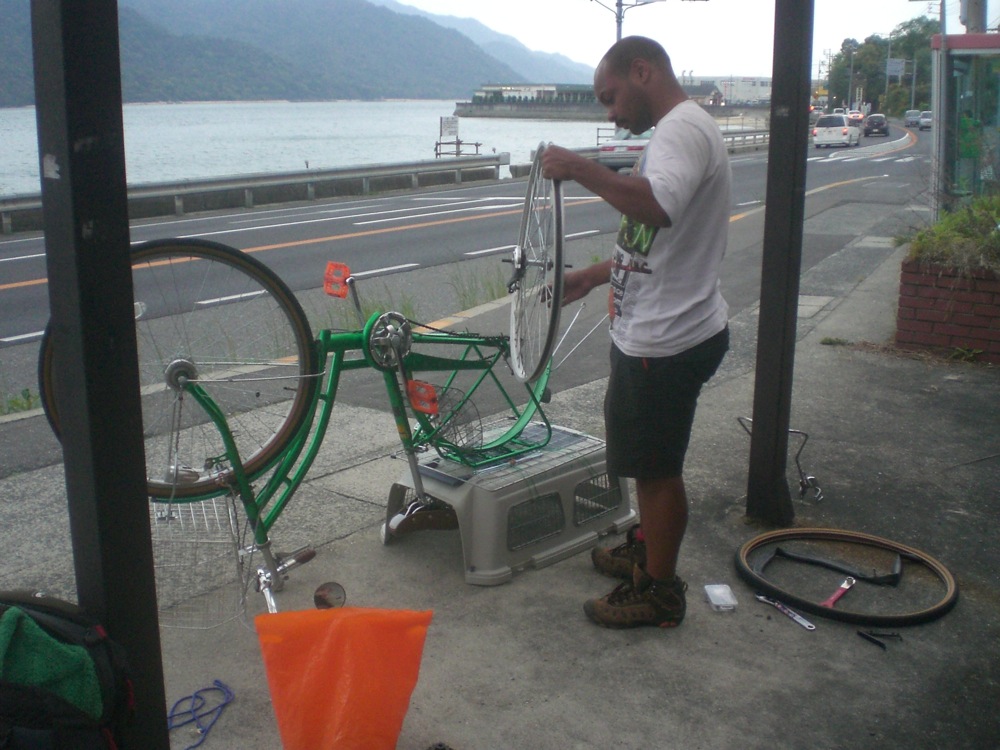 Petit problème technique: François ne peut plus du tout avancer tant sa roue arrière s'est voilée! Réparation forcée, 2h, dont une partie à l'abri de la pluie sous un abri