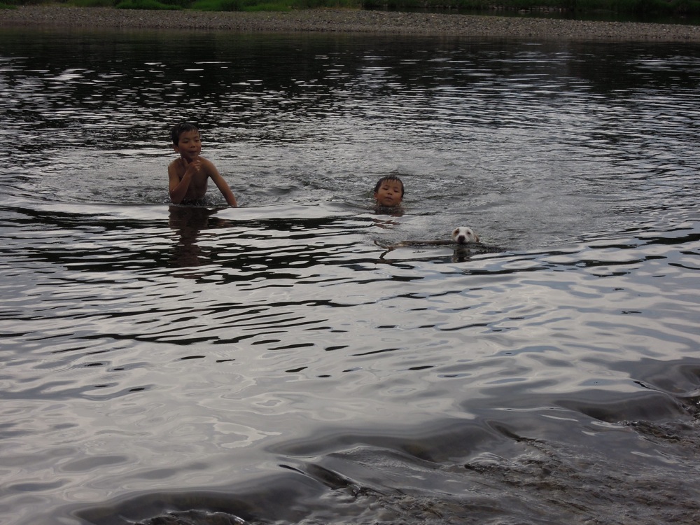 Les enfants nagent avec Carlo lorsqu'il va chercher le bâton!