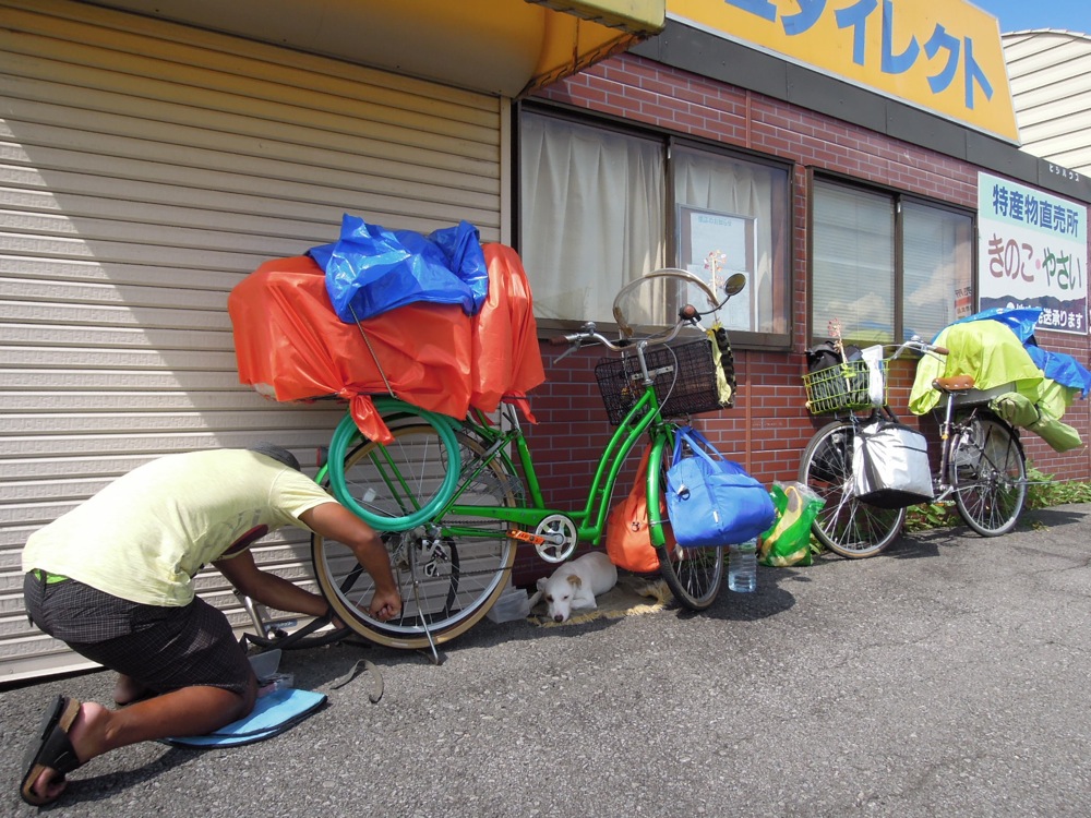 À peine 20km depuis la réparation de la chambre à air par un papi désagéable à Asahikawa: et il faut recommencer! La chaleur est de plomb. Impossible de trouver de l'ombre pour nous. On met Carlo à l'abri comme on peut!